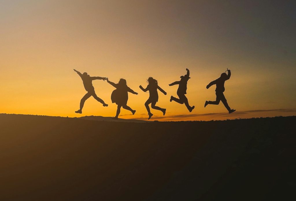 Group of friends jumping joyfully during sunset in Iceland, symbolizing freedom and happiness.